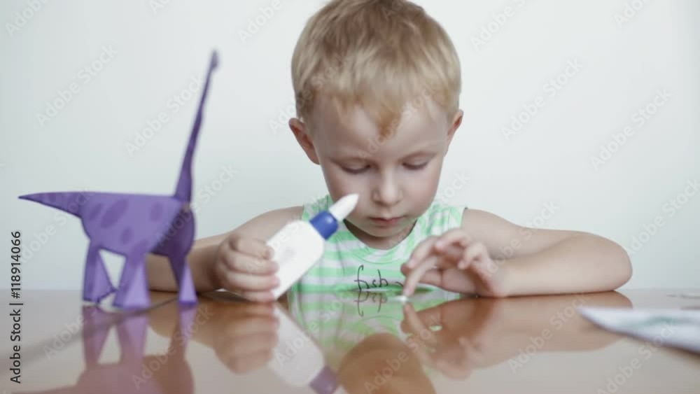 Little boy glues paper on white background. Little boy glues paper on white background.