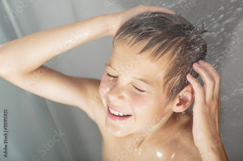 Happy teen boy washing head in shower in the bathroom