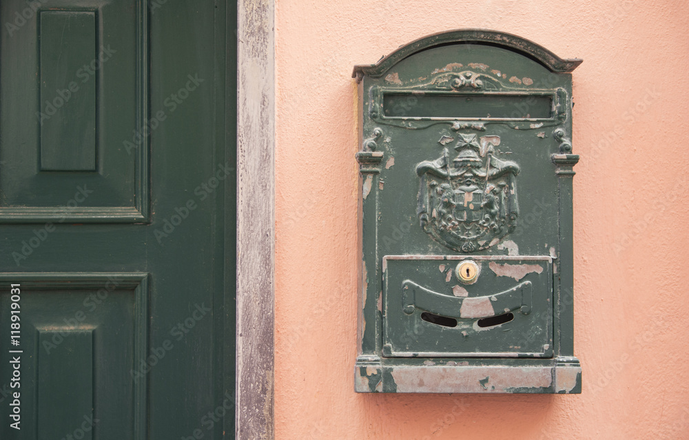 Green metal letterbox beside a green door over a pink wall - Classic vintage letterbox - Italian decor style