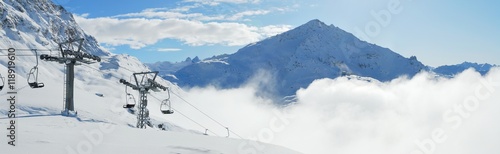 Winter mountains view with ski lift in the foreground and clouds in the valley. Corvatsch, Engadin, Switzerland.