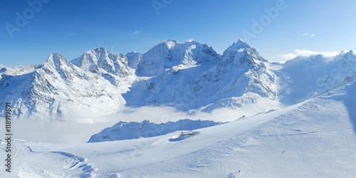 Winter mountains panoramic view with clouds in the valley and small hut. Corvatsch  Engadin  Switzerland.