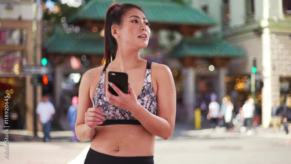 Japanese woman jogger using phone in the city Japanese woman jogger using phone in the city