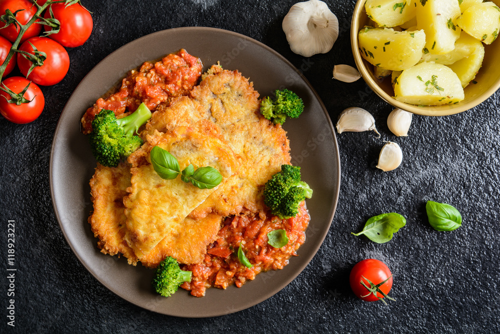 Piccata fried pork cutlets stuffed with smoked ham slices coated in cheese and eggs served