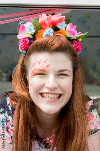 Red haired lady in dress with facepaint wearing flower headband