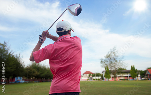 Men hit swing shot on course in summer day