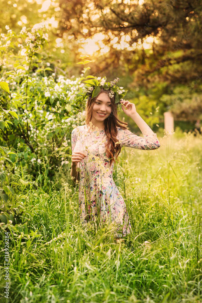 Beautiful young woman in a flower wreath in the park Beautiful young woman in a flower wreath in the park