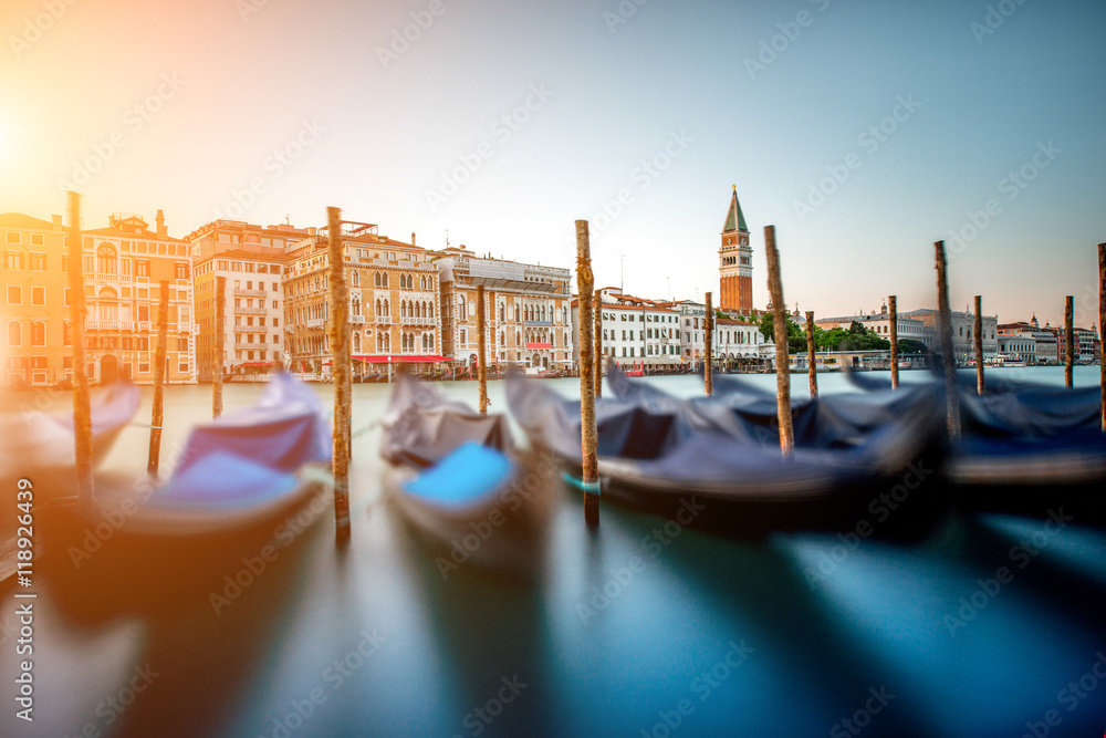 Venice cityscape view on Grand canal with colorful buildings, gondolas and San Marco campanille at the sunset. Long exposure image technic with motion blurred boats and glossy water