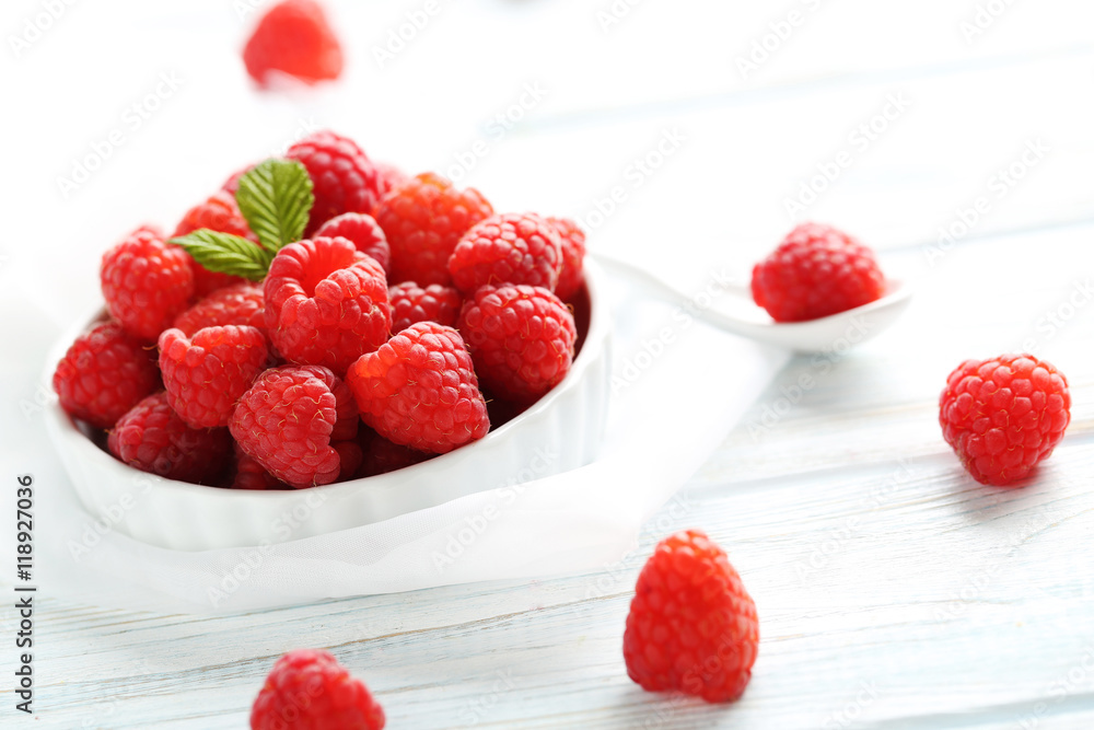 Red raspberries in bowl on a white wooden table Red raspberries in bowl on a white wooden table