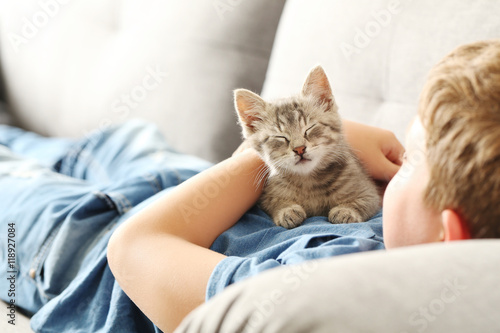 Child with kitten on grey sofa at home