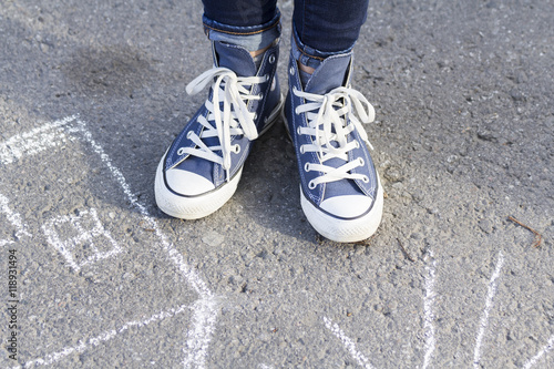Feet girl in sneakers cost about drawing a chalk on the pavement