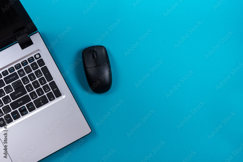 Office table desk with set of colorful supplies, white blank note pad, cup, pen, pc, crumpled paper, flower on blue background. Top view and copy space for text Office table desk with set of colorful supplies, white blank note pad, cup, pen, pc, crumpled paper, flower on blue background. Top view and copy space for text