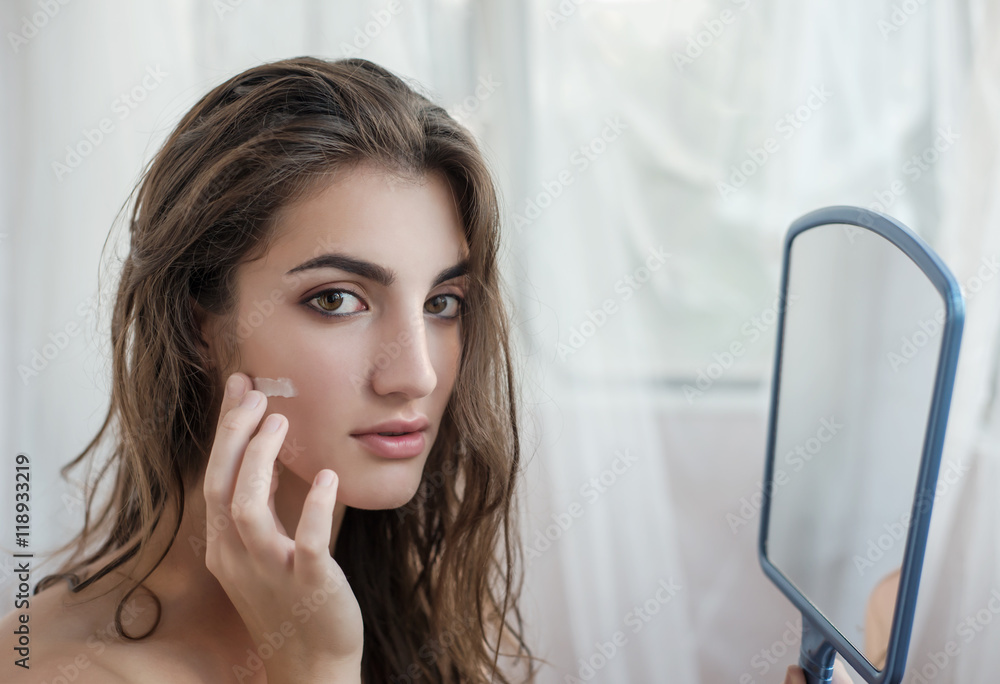 Beautiful model with wet hair in a towel after a shower applying Photos