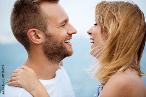 Young beautiful couple smiling, rejoicing, sea background.