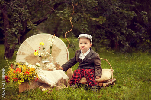 little boy in a jacket and plaid pants to sit on the cushion, ne