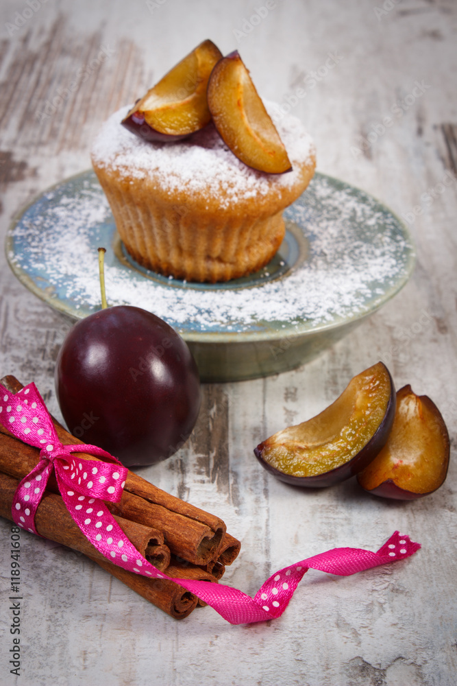 Fresh baked muffins with plums and powdered sugar on plate, delicious dessert