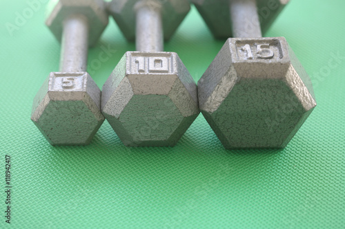 5, 10 and 15 pound weights in a row
Horizontal orientation photograph of 5, 10 and 15 pound weights in a row on a green mat
