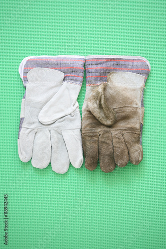 Clean and dirty work gloves
A vertical orientation photograph of two work gloves, one clean and one dirty, on a green mat
