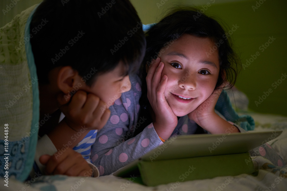 Smiling girl enjoying watching cartoons with her brother Smiling girl enjoying watching cartoons with her brother