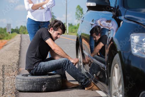 Man changing tire That are leaking His car broke down en route t