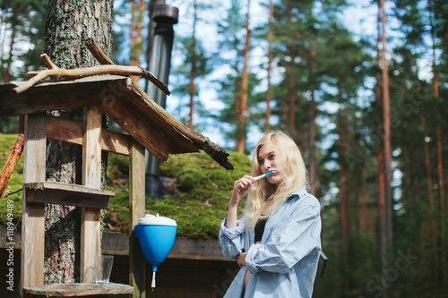 girl brushing teeth while in the woods near the house