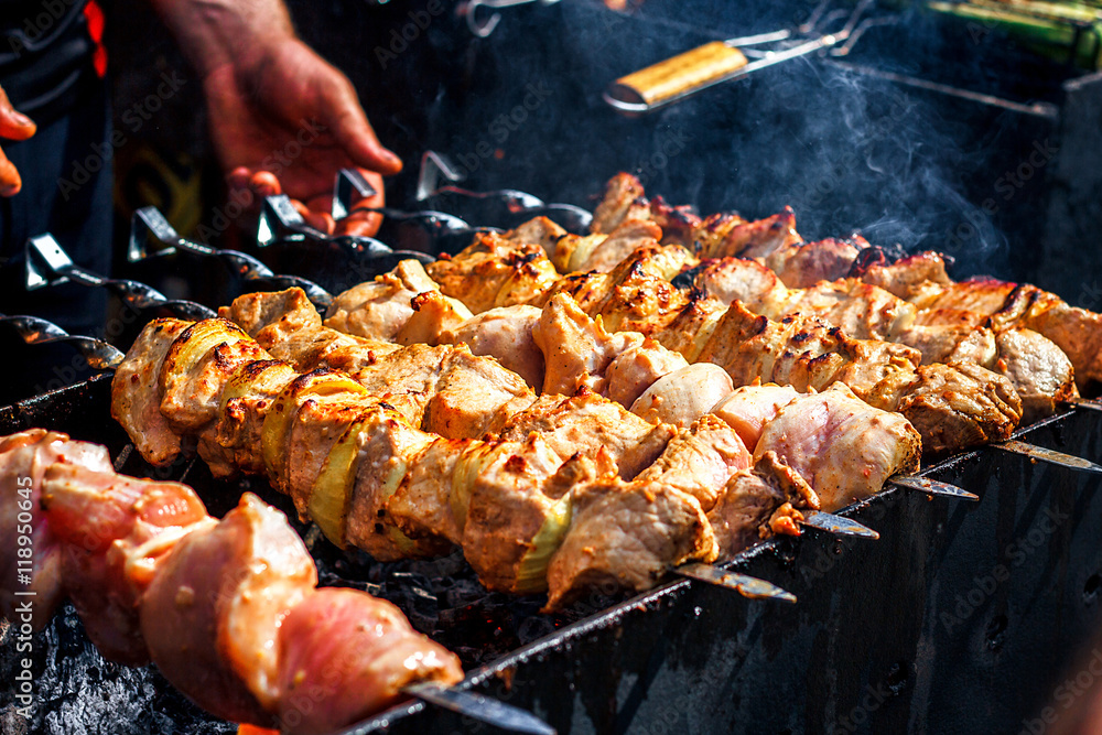 Grilling marinated shashlik preparing on a barbecue grill over charcoal.  Shashlik is a form of Shish kebab popular in Eastern Europe. Shashlyk (meaning  skewered meat) was originally made of lamb. Stock Photo