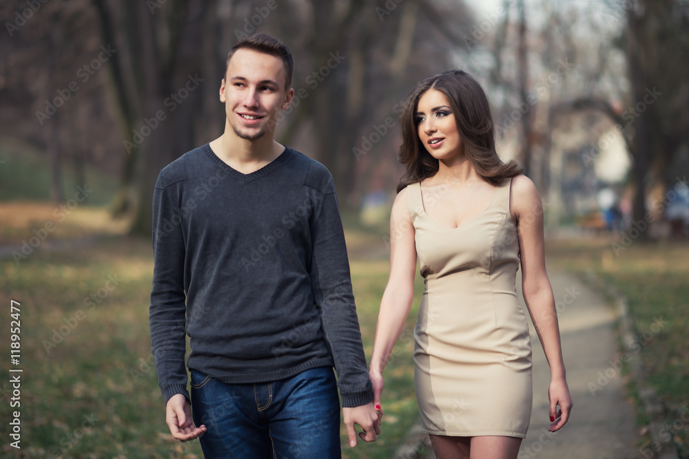 Young, happy and attractive couple enjoying together in walk through the city park. Urban outdoors. Young, happy and attractive couple enjoying together in walk through the city park. Urban outdoors.