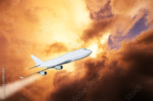 White plane jet engine flying through golden cloud on sky