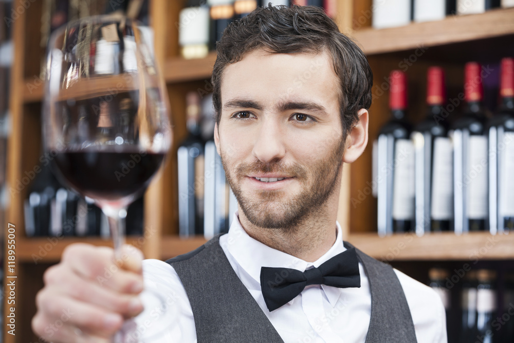 Bartender Examining Red Wine In Glass At Store Bartender Examining Red Wine In Glass At Store