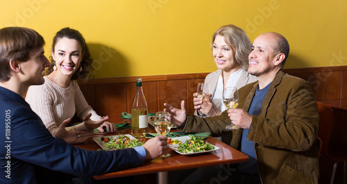 Four adults with wine and dinner laughing in restaurant