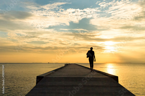 Man walks along the pier at sunset over the sea