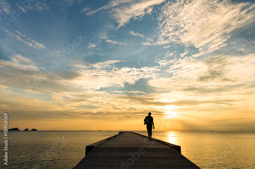 Man walks along the pier at sunset over the sea © mizuno555