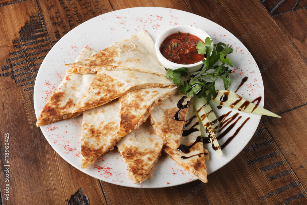quesadilla with beef and chicken on brown wood table. top view. quesadilla and sauce. quesadilla with beef and chicken on brown wood table. top view. quesadilla and sauce.