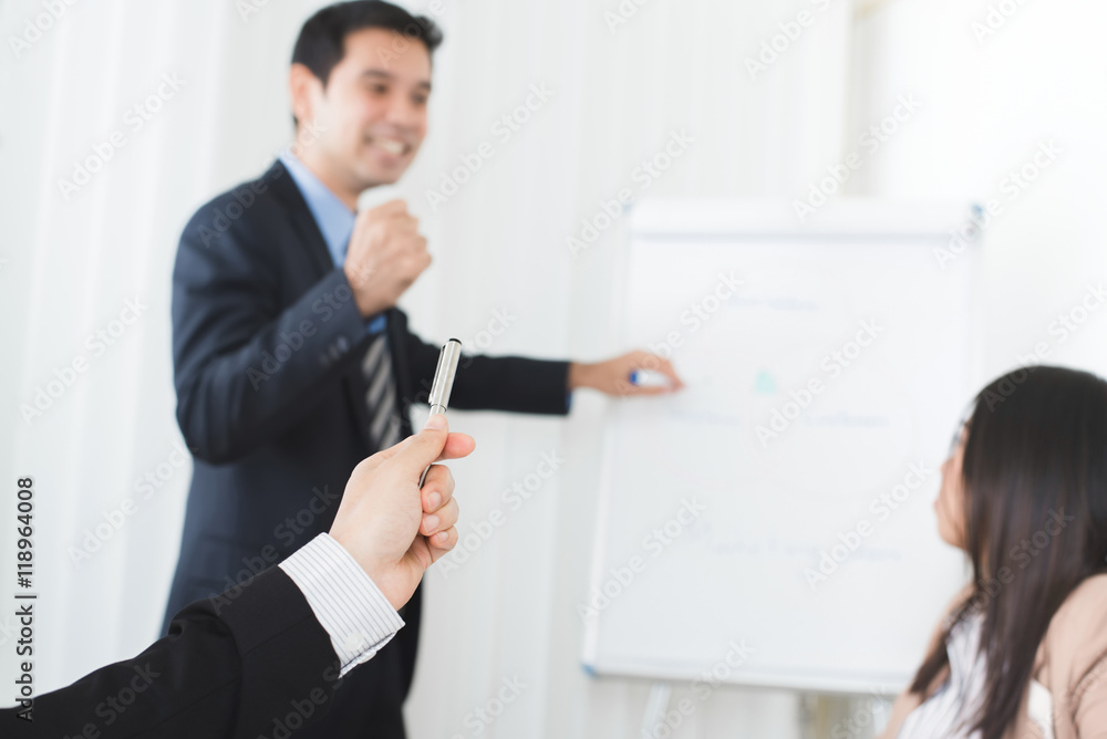 Businessman hand holding pen and pointing to powerful meeting leader Businessman hand holding pen and pointing to powerful meeting leader