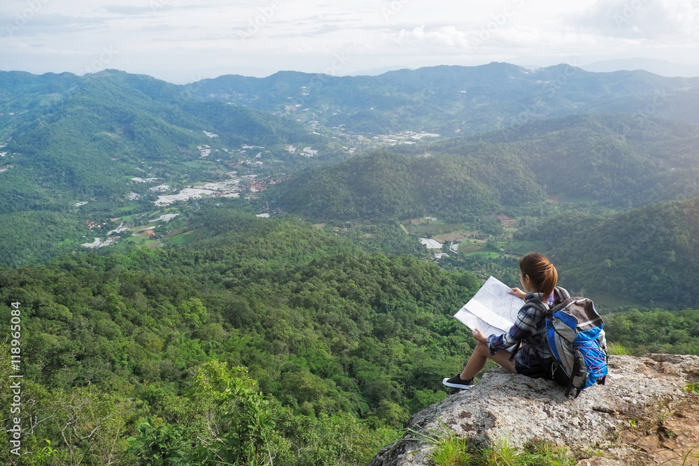 Young woman sitting on hill, looking at map, Hiking and Adventur