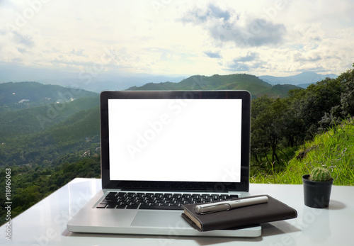 laptop over wooden table outdoors and blurred background of tree