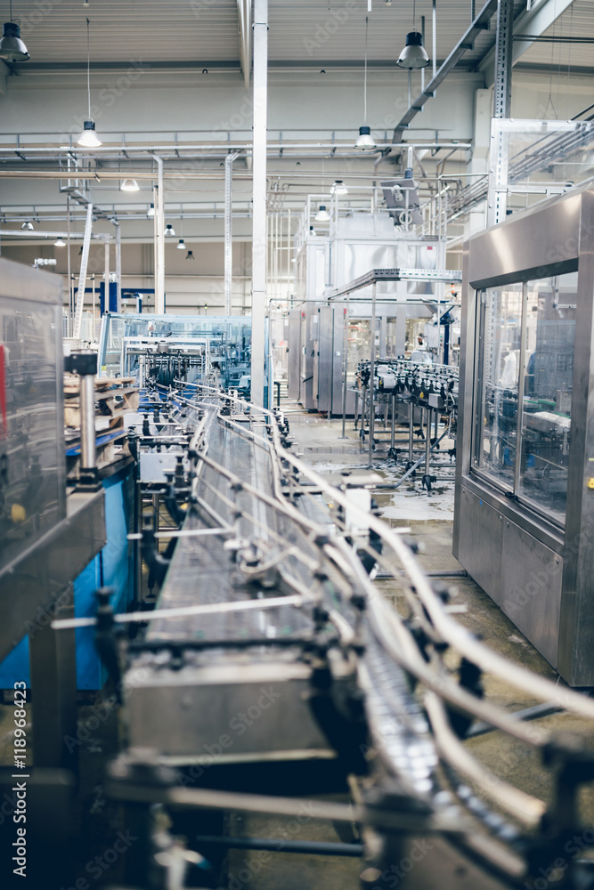 Industrial interiors. Robotic factory line for processing and quality control of pure spring water bottled into canisters. Low light and small amount of noise visible. 