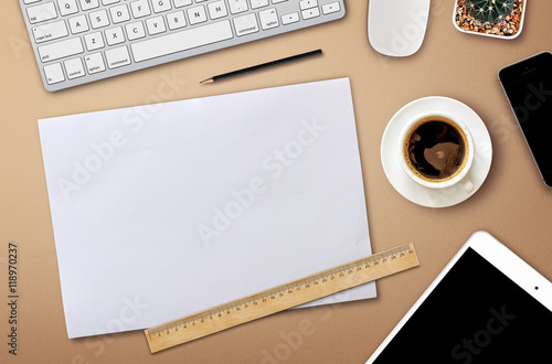 workplace with blank screen smartphone, tablet, coffee cup, paper and notebook on wooden table. top view with copy space. over light