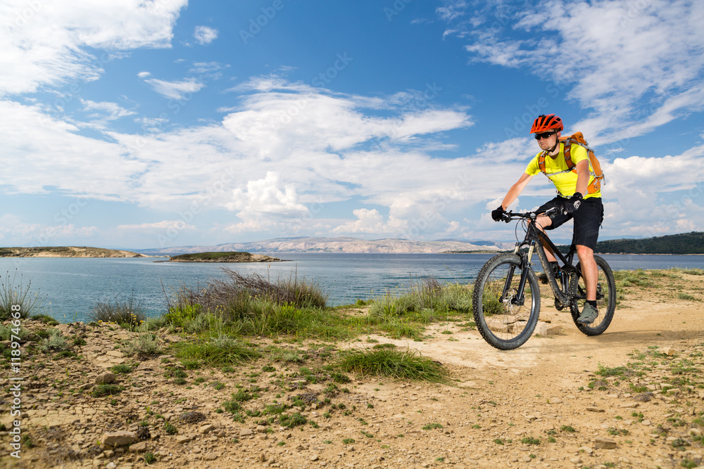 Fototapeta premium Mountain biker riding on bike at the sea and summer mountains. Sport and training outdoors.