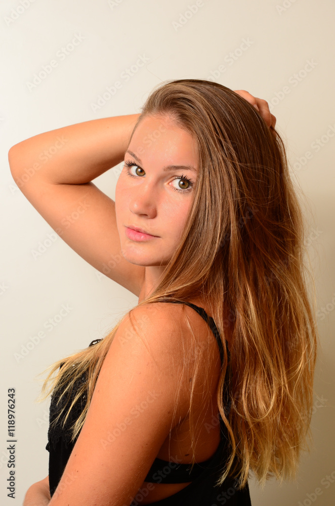 Naklejka premium junge Frau mit romantischem Blick greift sich ins lange Haar