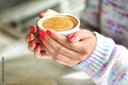 Woman hands holding cup of coffee in cafe
