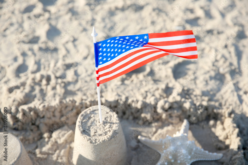 Naklejka premium Sand castle with American flag on beach