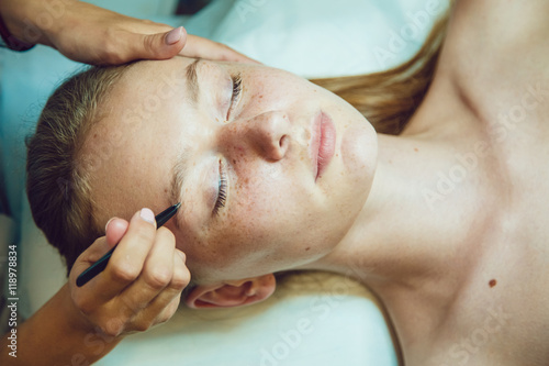 The workflow in a beauty salon girl plucked eyebrows. Tweezers.