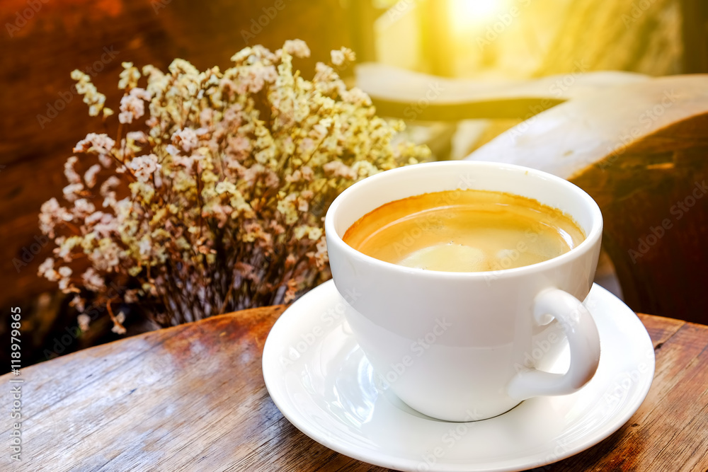 White coffee cup with dry flower on wooden table.Focus coffee wi White coffee cup with dry flower on wooden table.Focus coffee wi