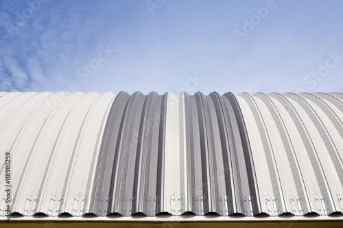 Modern construction. Metal ribbed arch-span roof covering. Looking up, front view.