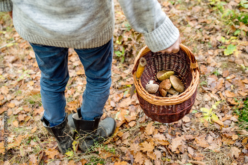 Unrecognizable man holding basket with mushooms, autumn forest