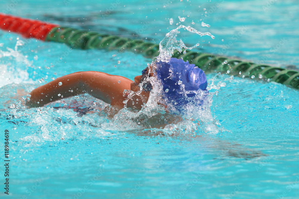 Young Asian man wearing blue cap practice freestyle stroke in a swimming pool