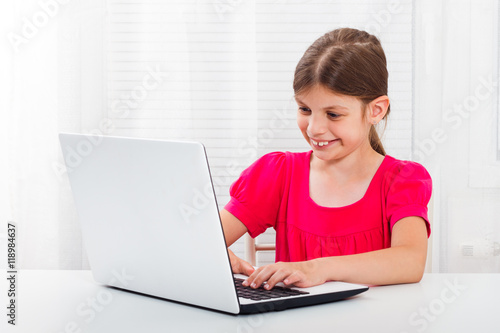 Cute little girl is using laptop.