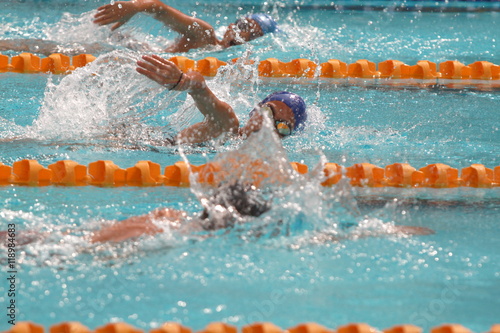A group of swimmers swim freestyle stroke in a swimming pool for competition or race