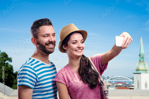 Couple with smartphone, taking selfie. Sunny summer city.