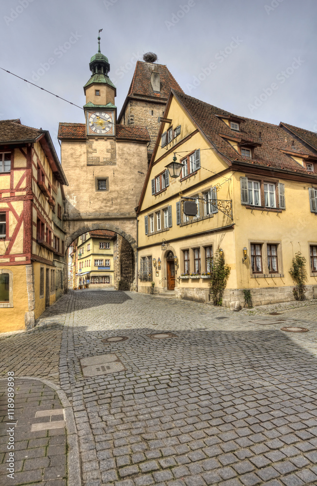 Historical street with ancient houses and hotels and an old gate and clock tower in Rothenburg ob der Tauber, Germany